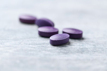 Purple pills on wooden background. Focus on foreground, shallow DOF.の写真素材