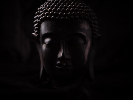 Buddha statue on black background, close-up, low keyの写真素材