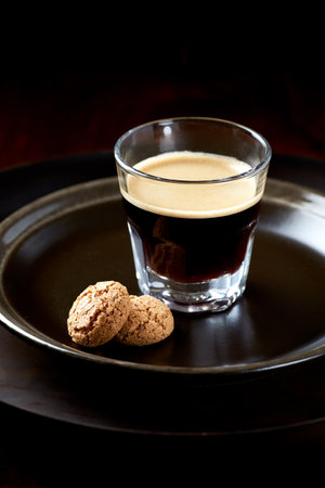 Espresso in a glass with cookies on a dark background.の写真素材