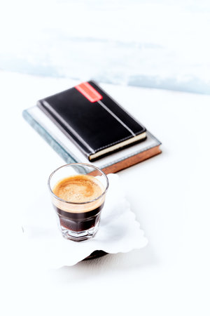 Espresso coffee in a glass with book on white wooden tableの写真素材