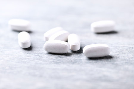 Heap of white pills on gray background. Focus on foreground, soft bokeh.の写真素材