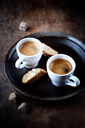 Two cups of coffee with bread on a dark background.の写真素材