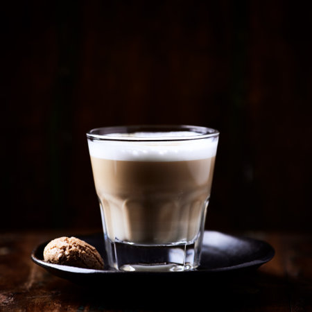 A glass of cappuccino on a dark wooden background.の写真素材