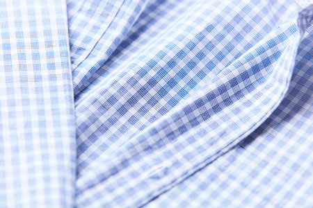 Close up of folded blue checkered shirt. Textile background
