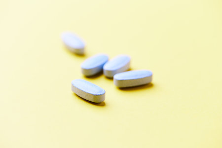 Pills on a yellow background. Focus on foreground, soft bokeh.