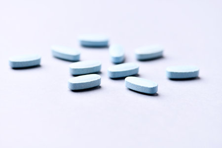 Blue pills on white background. Focus on foreground, soft bokeh.の写真素材
