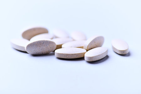 Heap of white pills on white background. Focus on foreground, soft bokeh.の写真素材