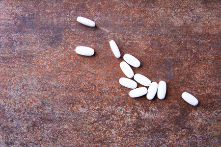 White pills on rusty metal background. Top view. Copyspace.