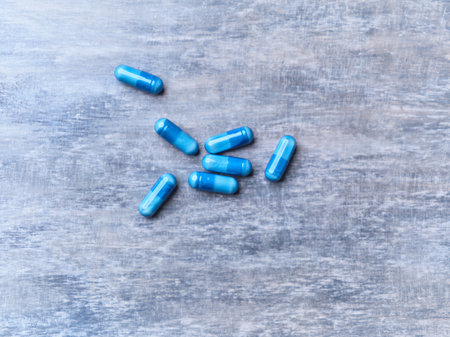 Blue pills on a wooden background. Top view. Copy space.