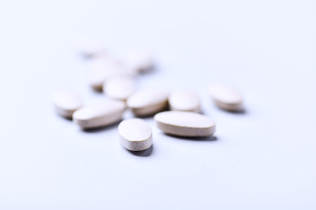Heap of white pills on white background. Focus on foreground, soft bokeh.
