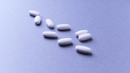 White pills on a blue background. Focus on foreground, soft bokeh.