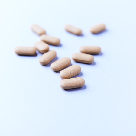 Heap of pills on blue background. Focus on foreground, soft bokeh.