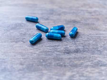 Blue pills on wooden background. Focus on foreground, soft bokeh.の写真素材