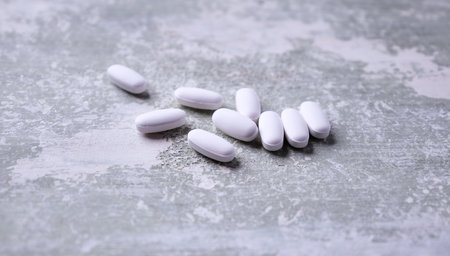 White pills on rustic wooden background. Focus on foreground, soft bokeh.