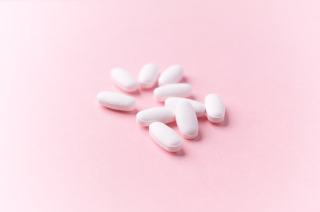 White pills on pink background. Focus on foreground, soft bokeh.の写真素材