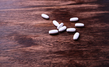 White pills on wooden background. Focus on foreground, soft bokeh.の写真素材