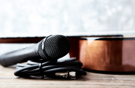 Microphone and acoustic guitar on a wooden table. Selective focus.の写真素材