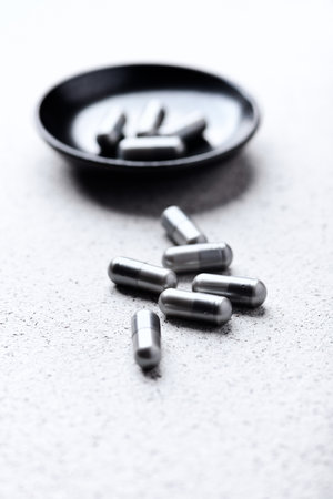 Pills on a black plate on a concrete background. Selective focus.の写真素材