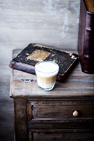 Coffee in a glass and old books on a wooden tableの写真素材