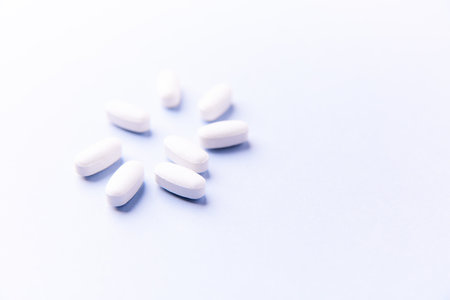 White pills on a white background. Focus on foreground, soft bokeh.