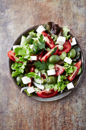 Greek salad with olives, feta cheese and herbs on rustic backgroundの写真素材