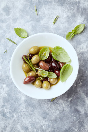 Bowl with olives, basil and olive oil on the tableの写真素材
