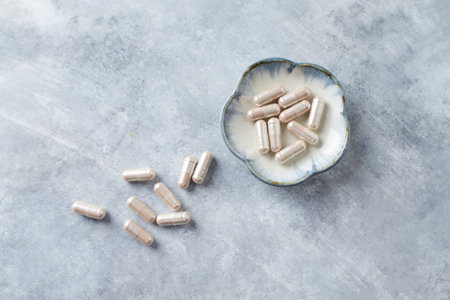 Capsules of dietary supplements in a bowl on a gray backgroundの写真素材