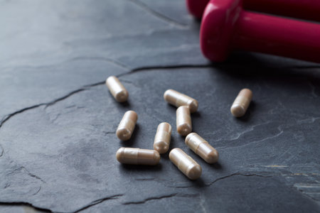 Pills and dumbbells on black stone background with copy spaceの写真素材