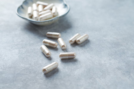 White capsules in a bowl on a gray background. Selective focus.の写真素材