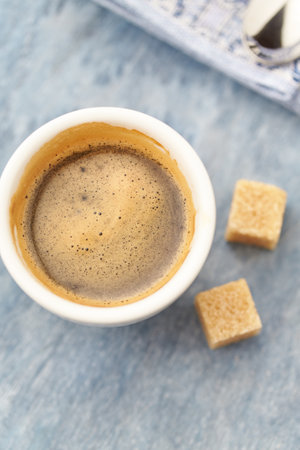 Cup of coffee with sugar cubes on a blue wooden background.の写真素材