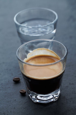Coffee espresso in a glass with coffee beans on dark backgroundの写真素材