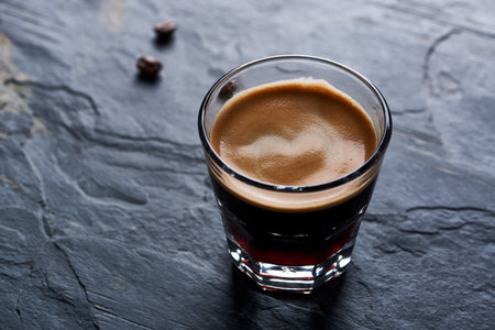 Coffee in a glass on a black stone background. Close-up.