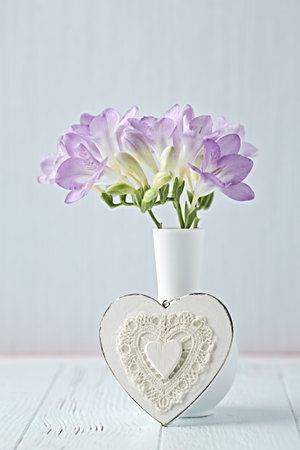 Bouquet of freesia in vase on white wooden backgroundの写真素材