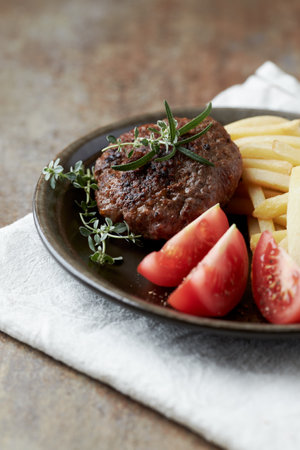 Grilled steak with french fries and tomatoes on a dark background.の写真素材