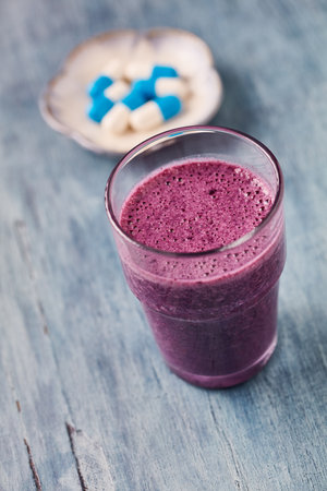 Blueberry smoothie in a glass on a blue wooden backgroundの写真素材