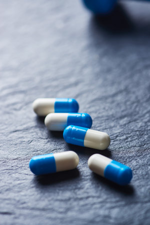 Blue and white pills on black slate background. Focus on foreground.の写真素材