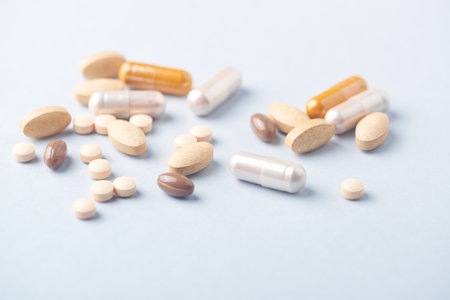 Pills and capsules on blue background. Focus on foreground, shallow DOF.