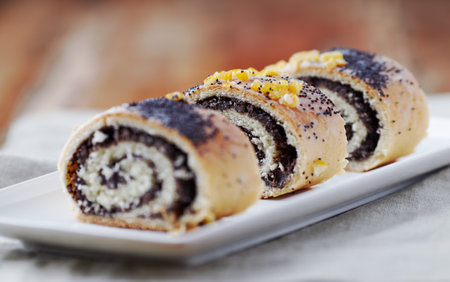 Poppy seed roll with poppy seeds on white plate, selective focus