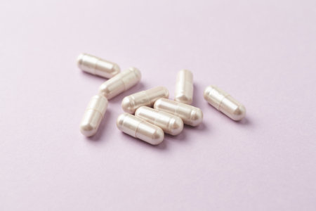Capsules of white color on a pastel pink background.の写真素材