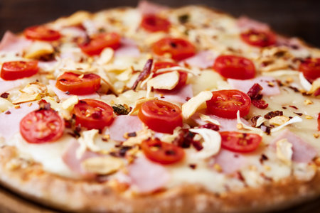 Pizza with ham, mozzarella and tomatoes on wooden backgroundの写真素材