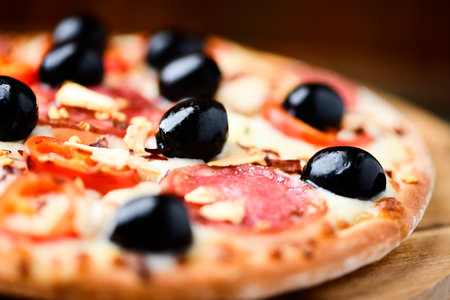 Pizza with salami, olives and cheese on wooden backgroundの写真素材
