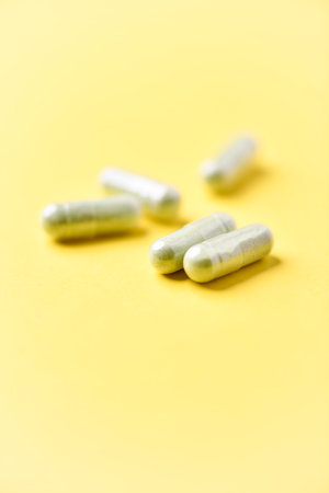 Close up of white pills on yellow background. Focus on foreground.