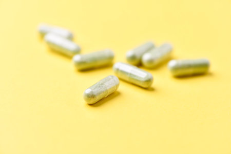 Close up of capsule pills on yellow background. Focus on foreground.の写真素材