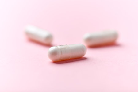 White pills on pink background. Focus on foreground, soft bokeh.の写真素材