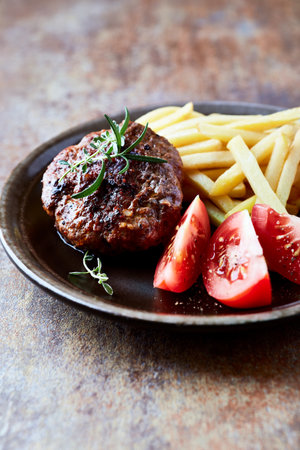 grilled hamburger with french fries and tomato, rustic styleの写真素材