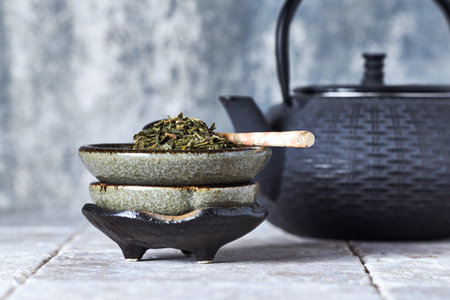 Green tea in a ceramic bowl and teapot on a wooden tableの写真素材