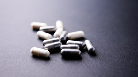 Pills and capsules on black background. Focus on foreground, soft bokeh.
