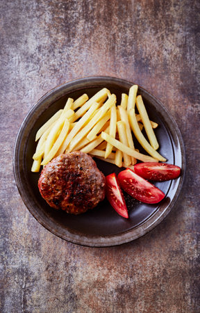 Grilled hamburger with french fries and tomato on a dark backgroundの写真素材