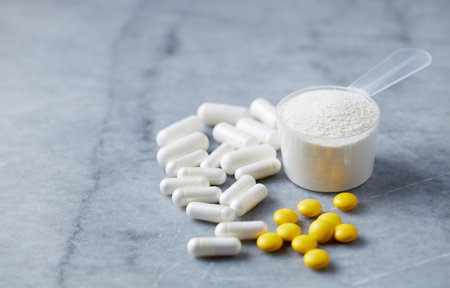 Pills and whey protein powder in scoop on gray background.の写真素材