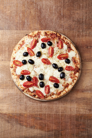 Pizza with tomatoes, olives and cheese on a wooden background